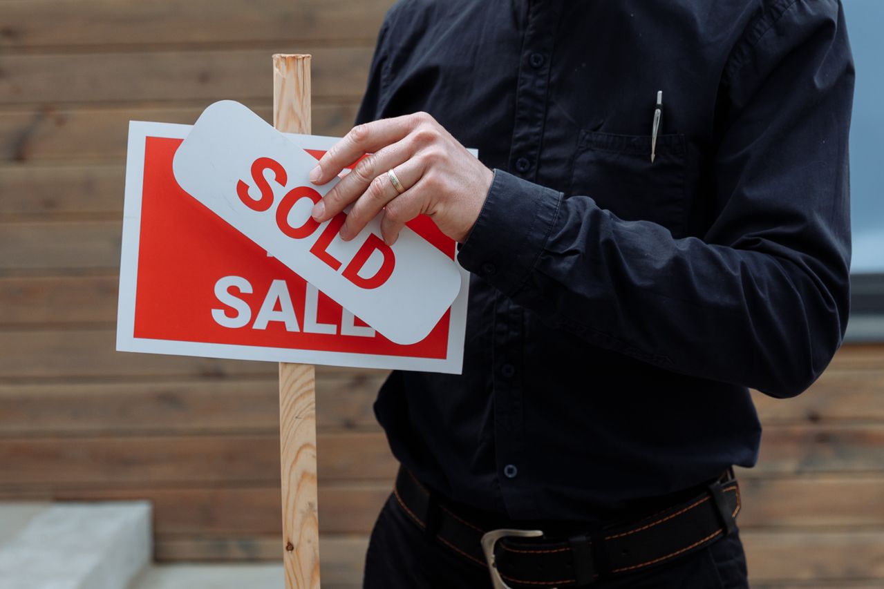 Estate agent που τοποθετεί πινακίδα Sold μετά την ολοκλήρωση αγοράς ακινήτου
